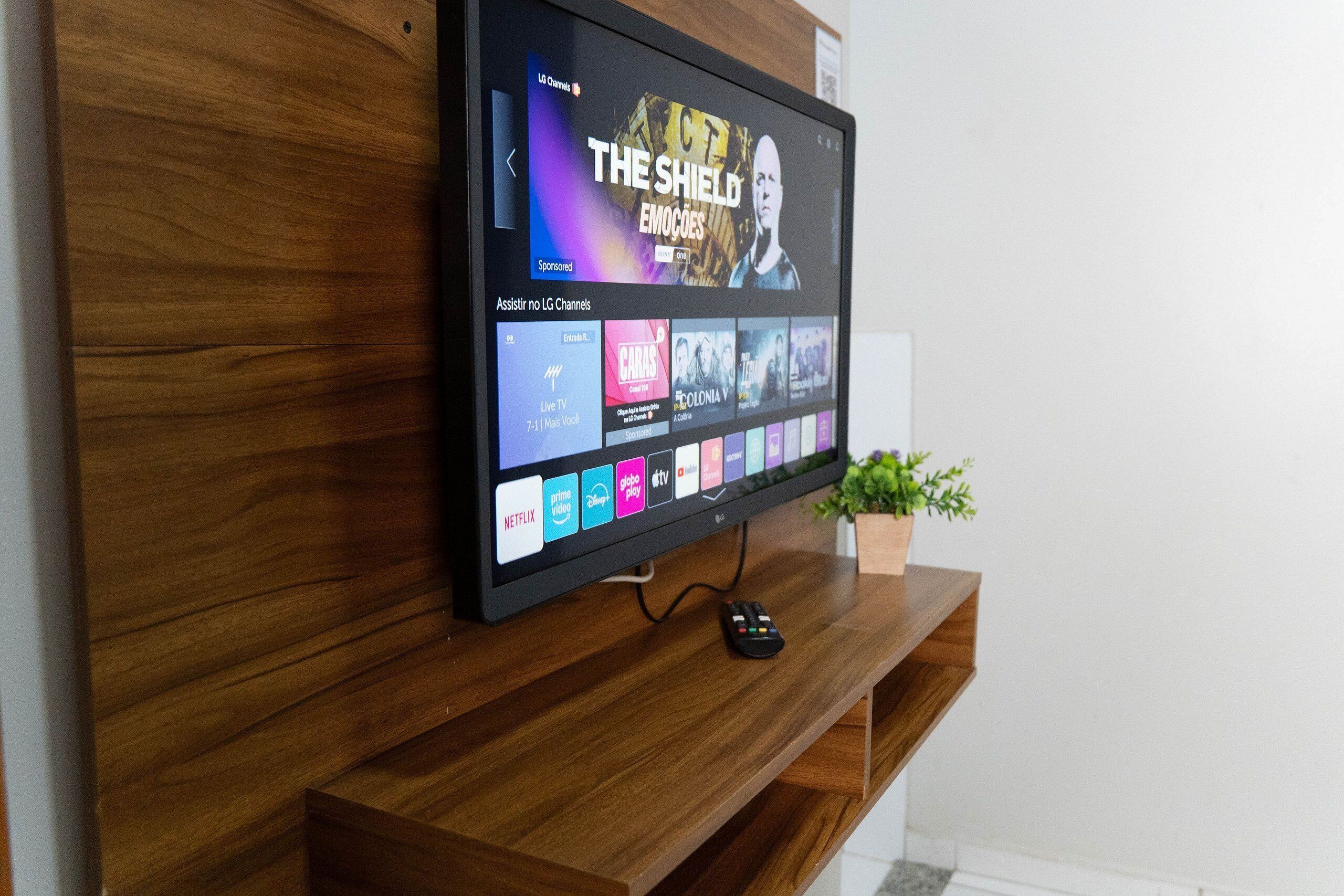 A flat-screen TV mounted on a wooden wall, displaying a streaming service interface with various content options.