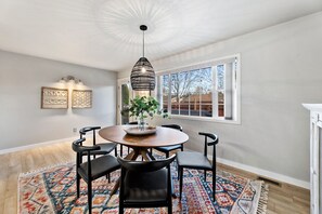 Enjoy meals in this cozy dining area with a round table and six chairs, a pendant light, and a potted plant.