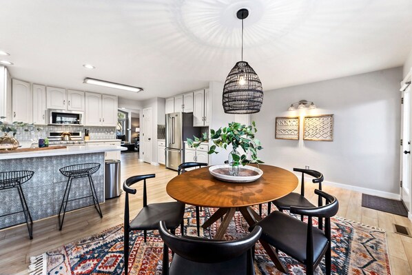 Enjoy meals around the central table, surrounded by comfortable seating and a potted plant.