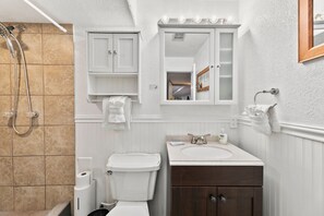 A bathroom with a toilet, sink, and shower. - Scandinavian Chic – Hot Tub, Bikes and Lake Life! (Loveland)
