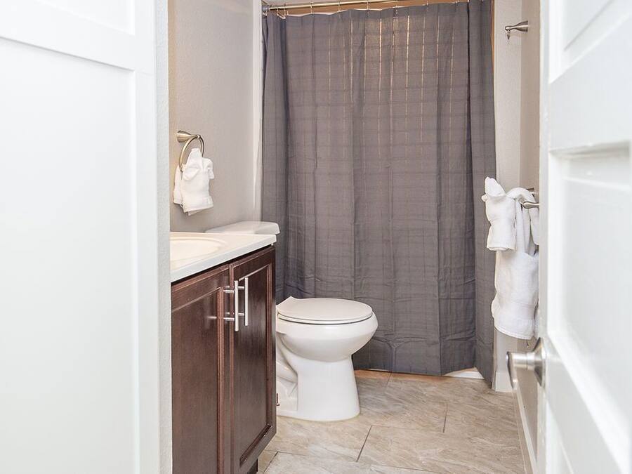 A bathroom with a toilet, a sink, a shower curtain, and a towel rack.