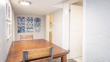 A dining area with a wooden table and chairs, patterned wall art, and a white door.