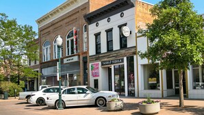 A street view with a white car parked in front of a building with a sign for 'Tacos & Tequila'. - Cozy Retreat | Walk to Unc | Free Cruiser Bikes (Greeley)