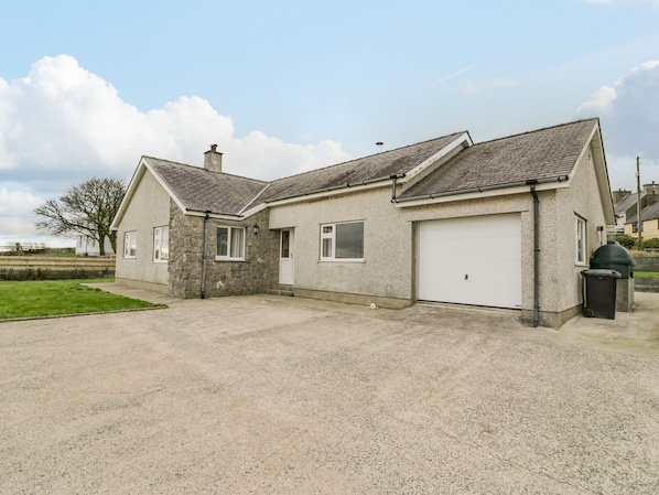 Une maison à deux étages avec une façade en pierre, un garage et une allée gravillonnée.