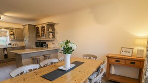 A modern kitchen with wooden cabinetry, a central island, and a dining area with a wooden table and chairs.