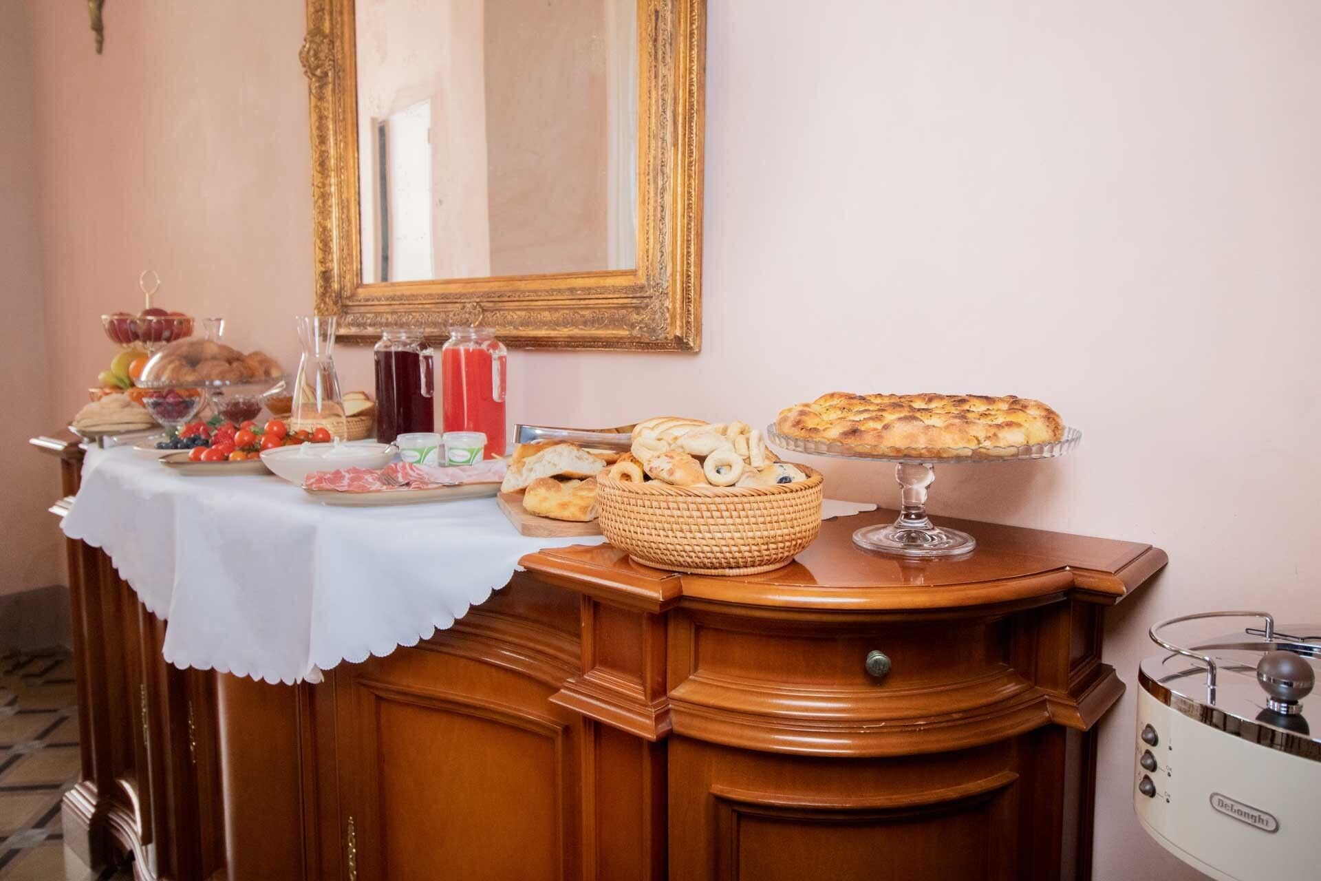 Una mesa de bufé con diversos alimentos, un espejo decorativo y una estufa de estilo antiguo.