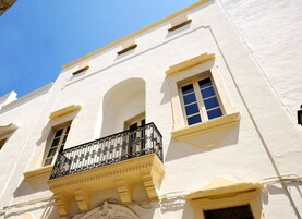 Un edificio blanco con balcón, ventana y arco.