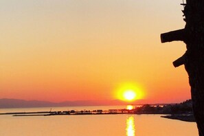 A sunset over a calm body of water with a pier extending into the water.