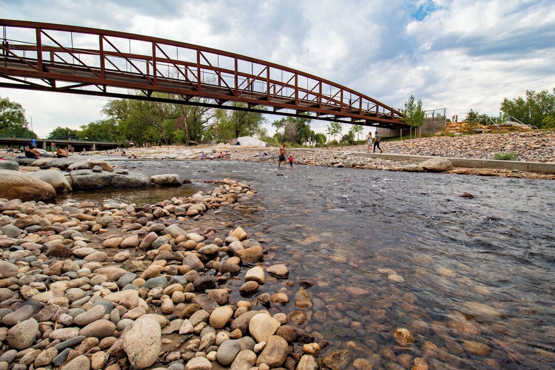 Un río con lecho rocoso y un puente metálico sobre él.