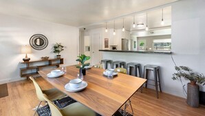 Un espace repas moderne avec une table en bois, des chaises et un coin bar équipé de tabourets.