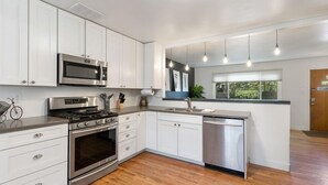 Une cuisine moderne dotée d’appareils électroménagers en acier inoxydable, de meubles blancs et d’un plancher en bois.
