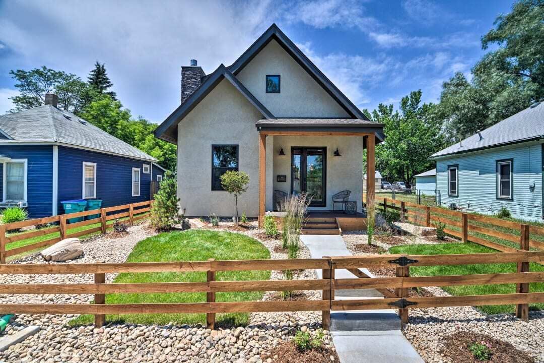 A modern house with a front porch, a fenced yard, and a gravel driveway.