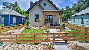 A modern house with a front porch, a fenced yard, and a gravel driveway.