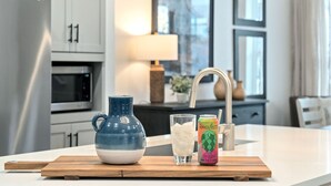 Ett modernt kök med ett kylskåp i rostfritt stål, en mikrovågsugn och en bänkskiva i trä.