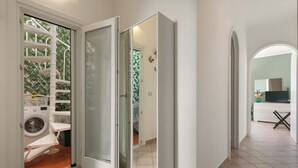 A laundry area with a washing machine and drying rack, a door leading to a hallway, and a kitchen area with a sink and countertop visible. - 3135 La Voce del Mare by Barbarhouse (Nardò)
