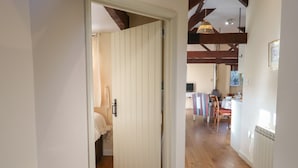 Corredor que dá para um quarto com assoalho de madeira e porta branca.