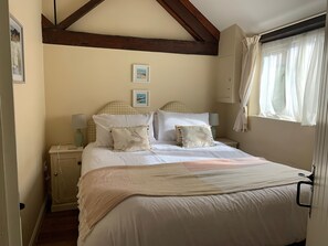 A bedroom with a bed, nightstands, a window with curtains, and a picture on the wall. - The Calf Pen (Colyton)