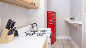 A compact kitchen with a white stove, a red refrigerator, and wooden cabinets.