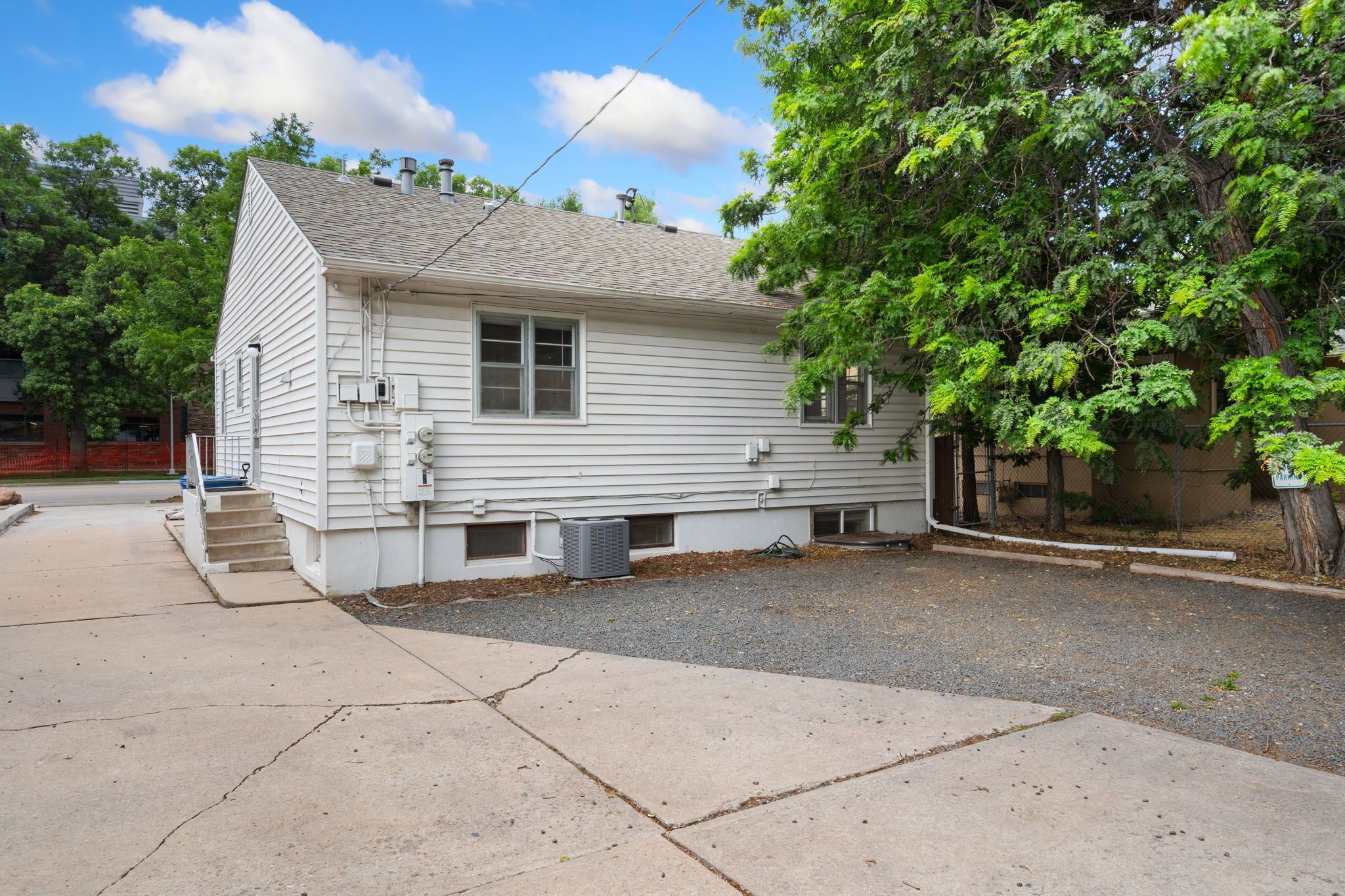 A single-story white house with a sloped roof, a front porch, and a small front yard.