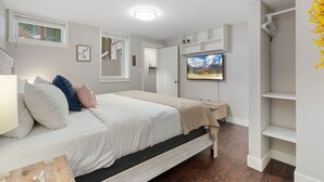 Une chambre à coucher avec un lit, un téléviseur fixé au mur et une étagère.