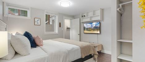 Un dormitorio con una cama, un televisor montado en la pared y una estantería.