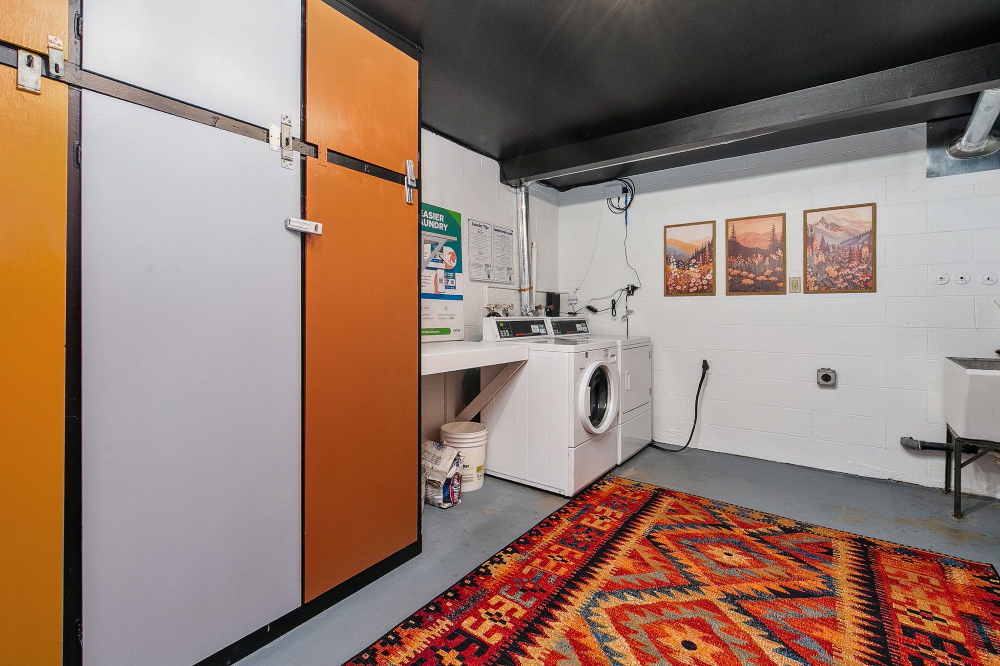 A laundry room with a washing machine, a drying rack, and a colorful rug.