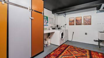 A laundry room with a washing machine, a drying rack, and a colorful rug.