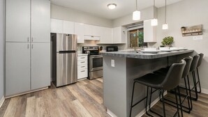 A modern kitchen with stainless steel appliances, a central island with bar stools, and pendant lighting. - Lavender Suite Relaxed, Walkable Old Town Stay (Fort Collins)