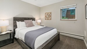 A bedroom with a bed, two bedside tables, a ceiling fan, a window, and a wall-mounted artwork. - Lavender Suite Relaxed, Walkable Old Town Stay (Fort Collins)