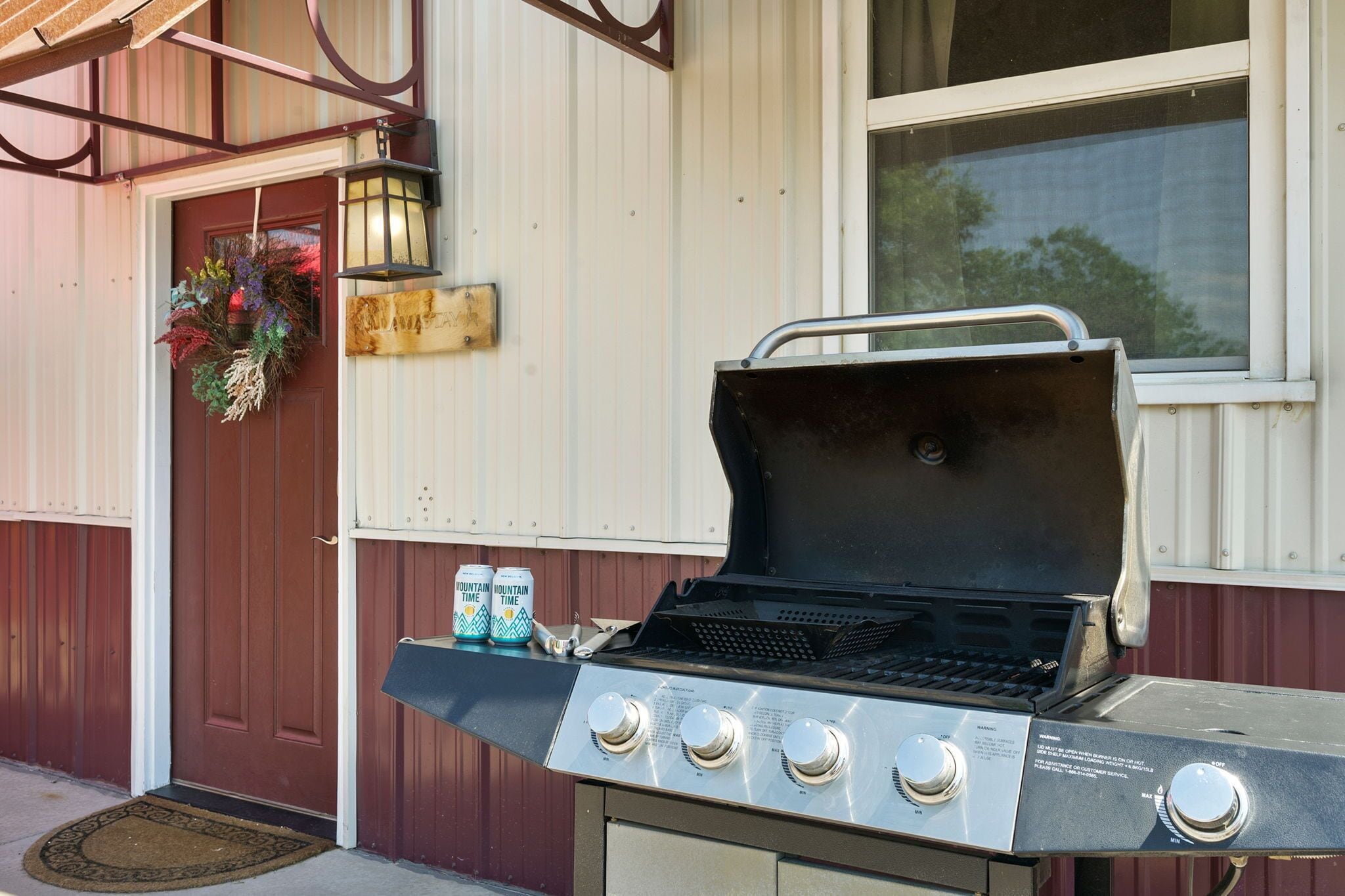 A barbecue grill with four control knobs, a metal handle, and a black lid.