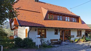 A traditional house with a red-tiled roof, a wooden front porch, and a cobblestone driveway. - Vacation apartment at Fuchsbühl  (Schopfheim)