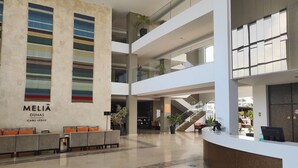 Una moderna hall dell'albergo con reception, zona salotto e una scala che conduce ai piani superiori.