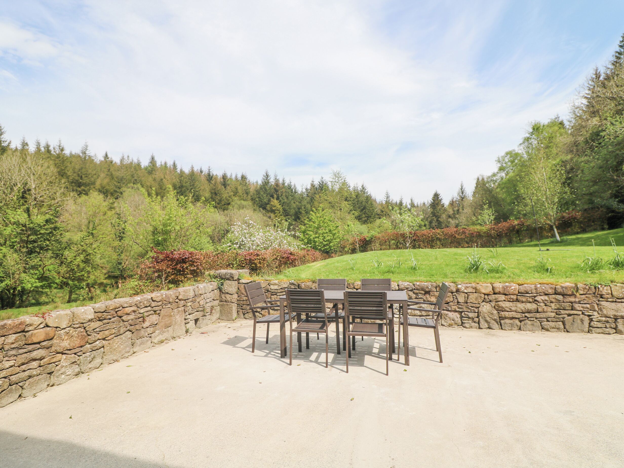 A patio with stone walls and a table and chairs set up.