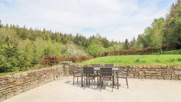 A patio with stone walls and a table and chairs set up.