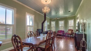 A dining room with a wooden table and chairs, a chandelier, and a fireplace.