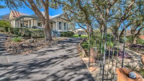 A residential property with a covered porch, a driveway, and a garden with a metal sculpture.