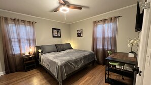 A bedroom with a bed, a desk, a ceiling fan, and curtains. - 3 bedroom brick ranch (Apex)