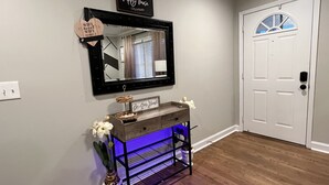 A hallway with a wooden console table, a mirror, and a sign that says "happy house." - 3 bedroom brick ranch (Apex)