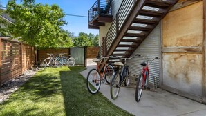 A residential building with a garage, a wooden fence, and bicycles parked outside. - Industrial Old Town Bungalow W/ Free Cruiser Bikes (Fort Collins)