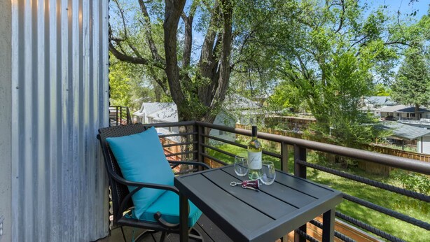 A balcony with a table, a chair, and a bottle of wine. - Industrial Old Town Bungalow W/ Free Cruiser Bikes (Fort Collins)