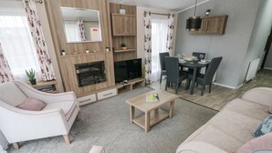 A modern living room with a fireplace, a dining area, and a seating arrangement. - Seahorse Retreat (Haverfordwest)
