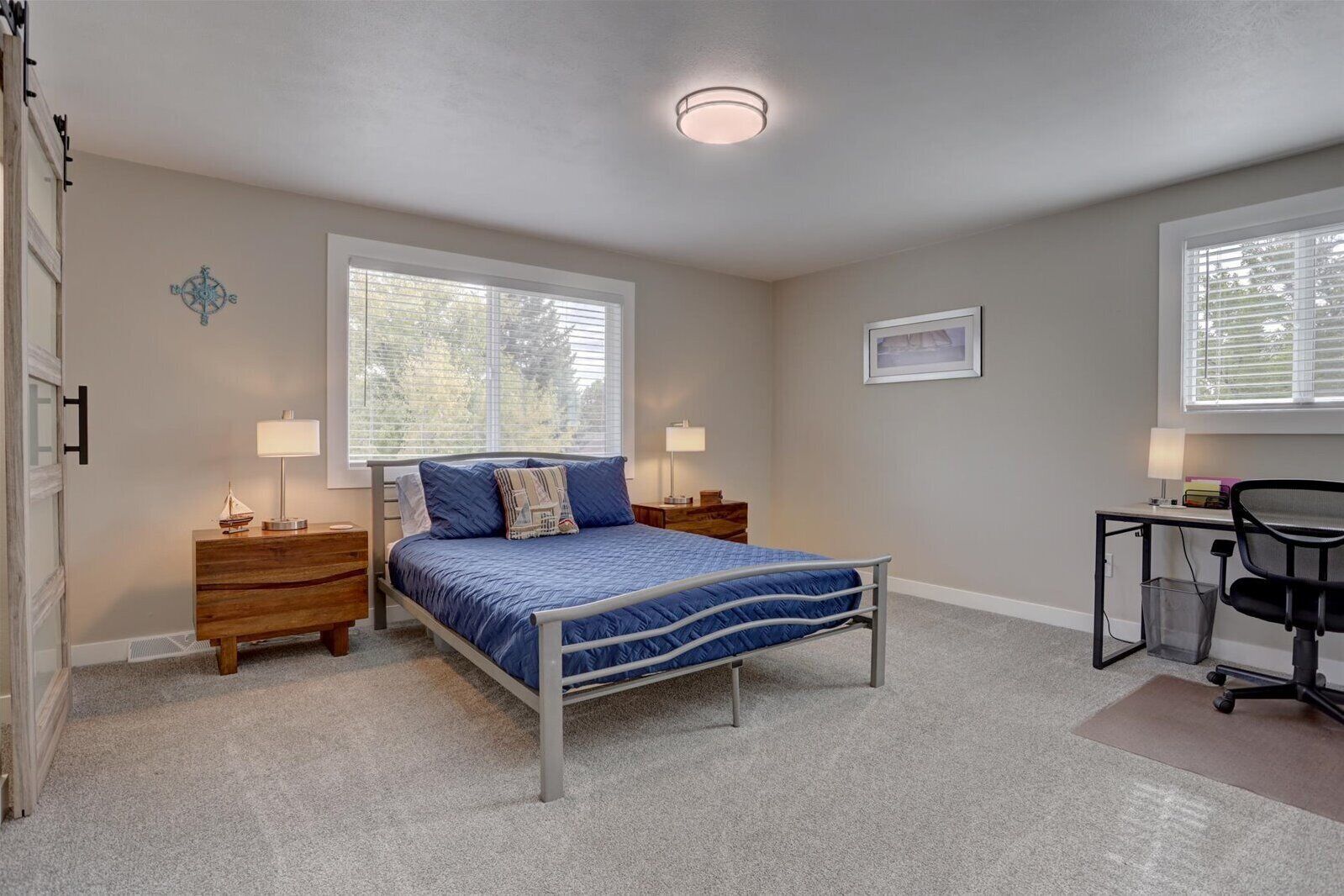 A bedroom with a bed, bedside tables, a desk, and a chair.