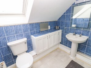 A bathroom with blue tiles, a white toilet, a white cabinet, and a white sink.