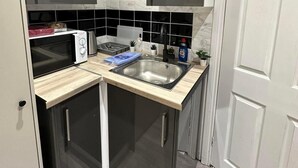 A compact kitchen with a microwave, toaster, sink, and a small countertop area. - Studio Sleeps 1 Near Acton Park (London)