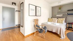 A modern bedroom with a bed, a chair, and two framed pictures on the wall. - Luxury Business Studio Apartment - Garden View (Sundbyberg)