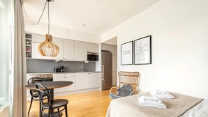 A modern kitchen with white cabinets, a stainless steel refrigerator, and a hanging pendant light. - Luxury Business Studio Apartment - Garden View (Sundbyberg)