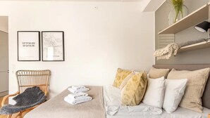 A bedroom with a bed, a chair, and two framed maps on the wall. - Luxury Business Studio Apartment - Garden View (Sundbyberg)