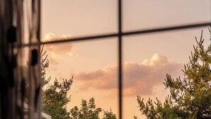 A window with a view of trees and a sunset sky. - Gapyeong Monami spa Pension (Gapyeong)