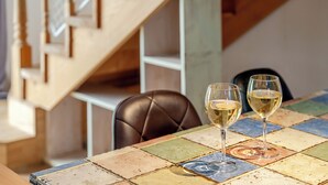 A table with two glasses of white wine, a brown leather chair, and a colorful tiled table surface. - Gapyeong Monami spa Pension (Gapyeong)