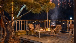 A deck with outdoor seating, a grill, and string lights. - Gapyeong Monami spa Pension (Gapyeong)